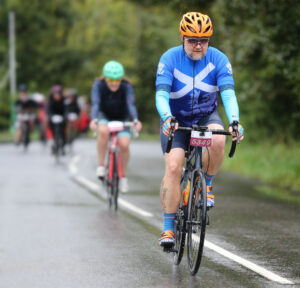 Gordon cycling in a blue cycle top bearing the Scottish saltire.