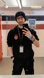 A mirror selfie of Ducky Dorman, he is wearing a Tigers hoodie, a beanie hat, glasses and a lanyard with a pass on the end.
