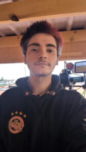 Robert MacRae with half his hair dyed red, wearing a Tigers hoodie and standing in front of the tower camera