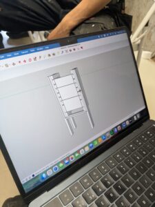 A laptop displaying a SketchUp 3D model of a wooden shelving unit.