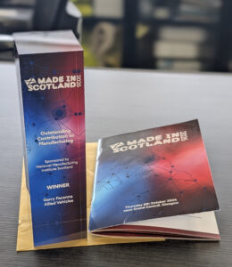 A Made in Scotland 2026 award trophy for Outstanding Contribution to Manufacturing, and an accompanying event programme for the 8 October 2026 ceremony in Glasgow.